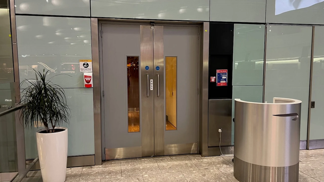 Discreet unmarked double doors and British Airways Speedbird podium before Terminal 5 escalators