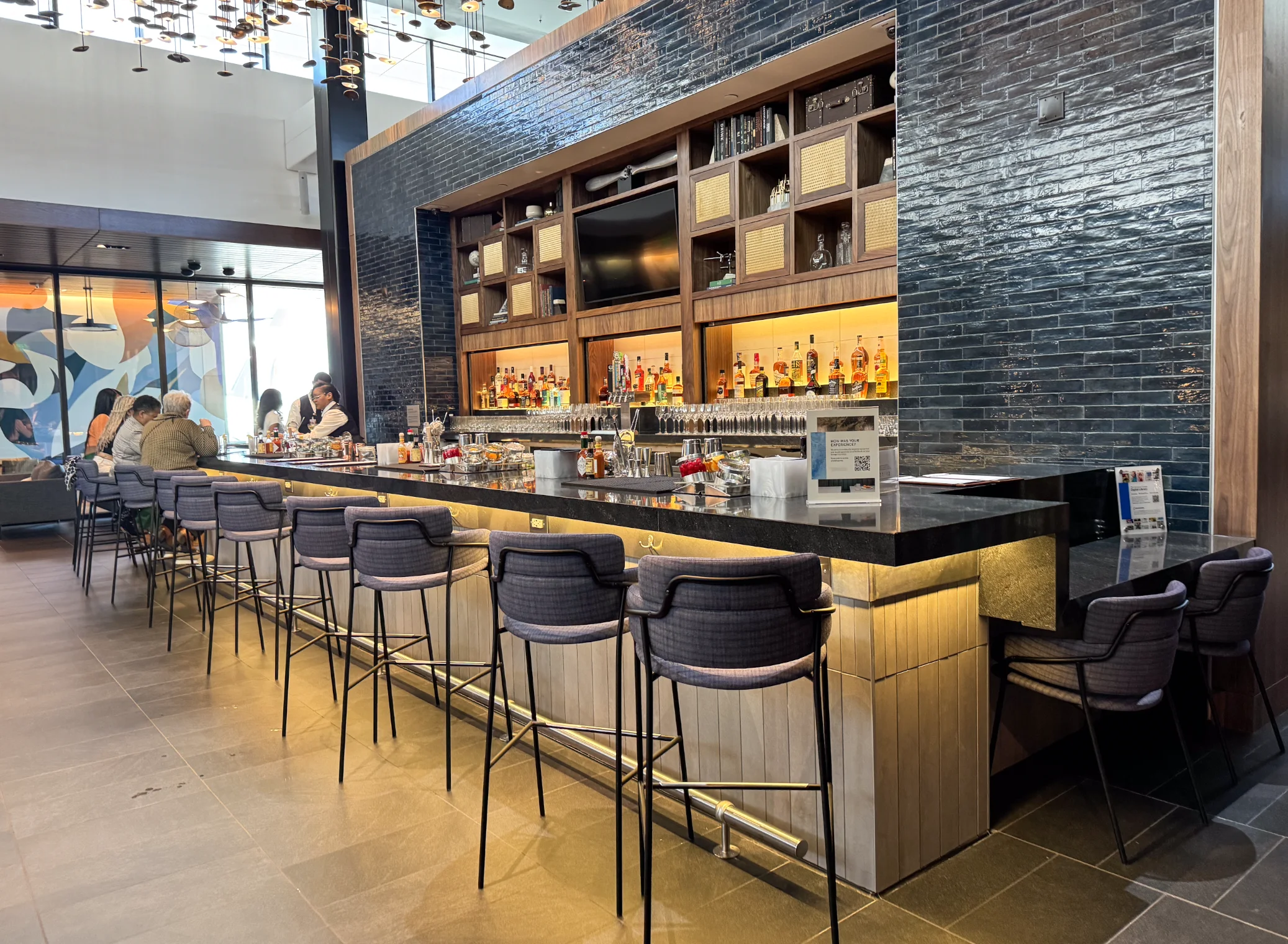 Amex Centurion Lounge cocktail bar with blue tile wall and backlit spirits shelves