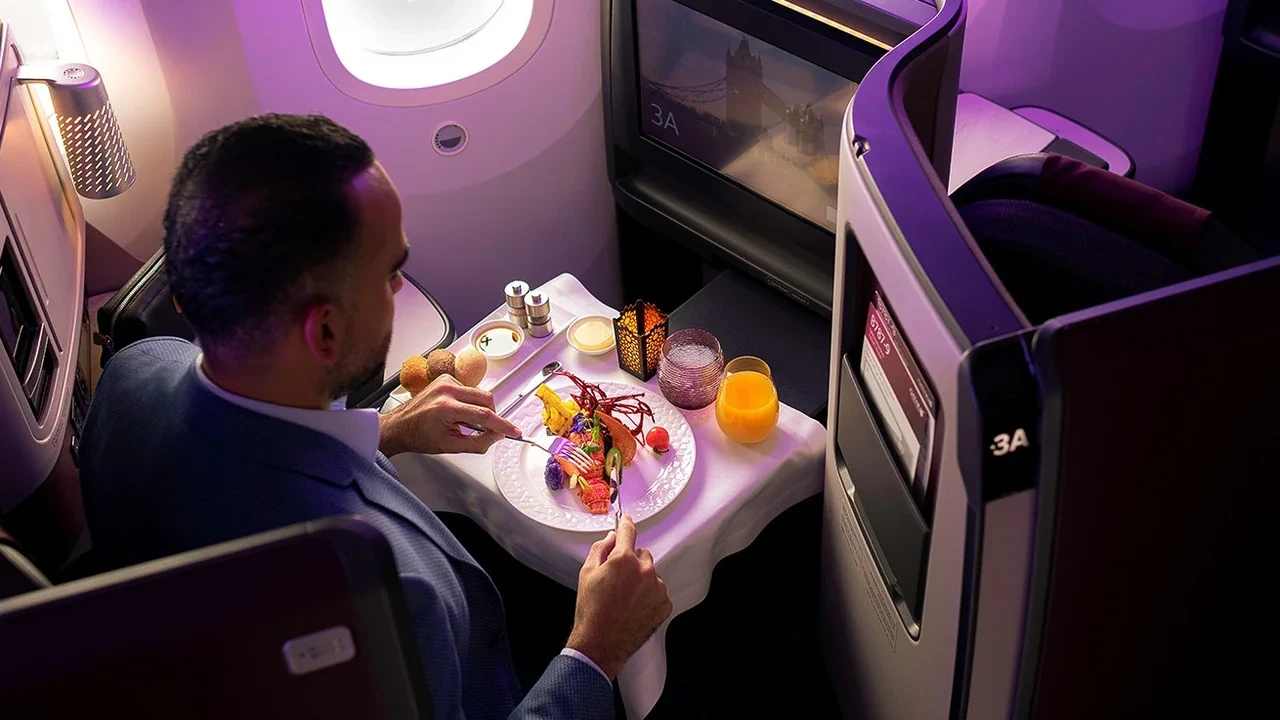 Qatar Airways business class table service with white linen, lobster main course, and candlelight